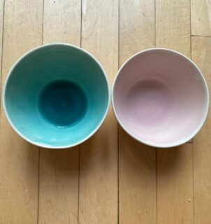I’ve been making this tableware range for 20 years, porcelain with a satin matt glaze on the outside and coloured glazes on the inside. I use the same base glaze, a runny, glossy transparent, to which I add various colouring oxides.

We use these bowls every day and it’s interesting to see how they fare in the dishwasher. The turquoise glaze containing 1% copper oxide is still glossy after hundreds of washes in the dishwasher. However, the pink glaze containing 2% rutile and 4% tin oxide has turned matt and has some faint metal marking from cutlery.

I had a look at the molecular formula of the glaze, it’s chemically stable with a flux ratio 0.3:0.7 alkali metals to alkaline earths. Both copper oxide and tin oxide act like alkali metal fluxes. However, the larger amount of tin oxide (4%, 0.1 in the UMF) is bringing the total alkali metal flux close to the 0.4:0.6 limit for chemically stable glazes. 

Tin is essential for the pink colour in chrome-tin pink glazes. In this glaze, the chromium is one of the impurities in the rutile. While rutile stabilises the glaze, this pink glaze is slightly less chemically stable owing to the addition of tin oxide.